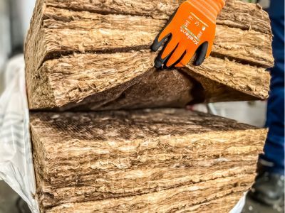 Hand mit Handschuh h&auml;lt dicke D&auml;mmstofflagen, zeigt Struktur und Dicke von Isoliermaterialien.